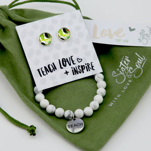 Bracelet and earrings set with 'Teach Love Inspire' card on green fabric