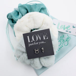 White fluffy ball with 'LOVE just for you' card and earrings on a light blue drawstring bag.