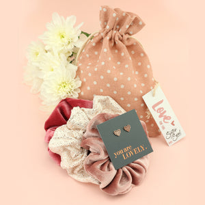 Set of scrunchies, earrings, and a polka dot bag on a pink background