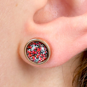 Close-up of an ear wearing a colorful stud earring.