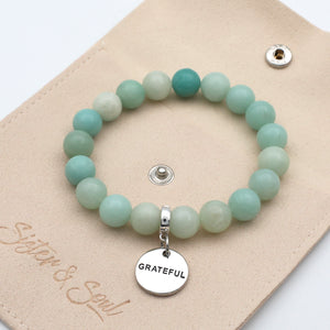 Turquoise beaded bracelet with a 'Grateful' charm on a beige card
