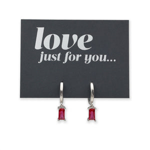 A pair of silver hoop earrings with rectangular red gemstones, displayed on a black card that reads 'love just for you...'.