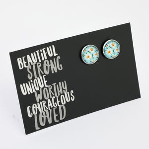 Floral earrings on a black card with motivational text