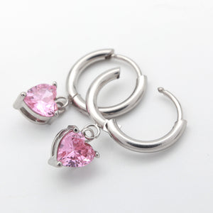 A pair of silver-toned hoop earrings with dangling heart-shaped pink gemstones, shown on a clean white background.