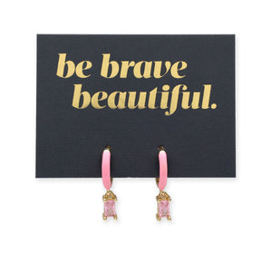 Pink earrings on a card with 'be brave beautiful' text