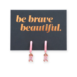 Pink earrings on a card with 'be brave beautiful' text