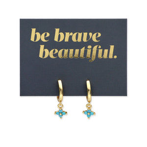 Gold hoop earrings with turquoise charms on a 'be brave beautiful' card.