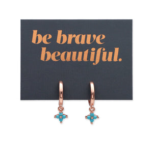 Rose gold earrings with turquoise stones on a card with 'be brave beautiful' text.
