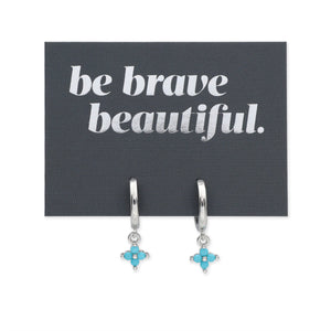 Silver earrings with turquoise stones on a card with 'be brave beautiful' text.