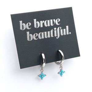 Silver earrings with turquoise stones on a card with 'be brave beautiful' text