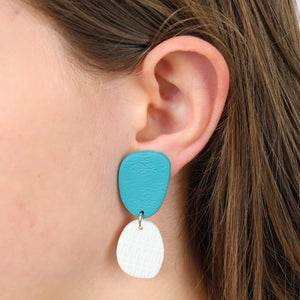 Close-up of a person wearing a turquoise and white earring.