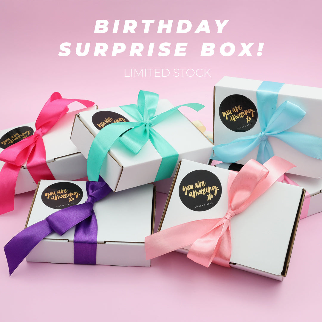 Mystery surprise gift box with colourful bows on pink background.