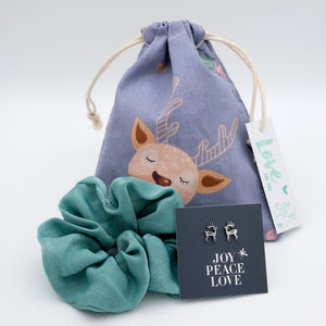 Teal scrunchie, deer-themed drawstring bag, and deer earrings on a light gray background