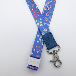 Floral patterned lanyard with blue strap and metal clip on a white background