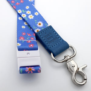 Floral patterned lanyard with blue buckle and metal clip on a white background