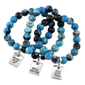 Blue and black beaded bracelets with motivational charms on a white background