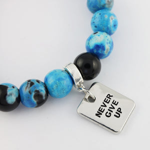 Bracelet with blue and black beads and a 'Never Give Up' charm on a white background