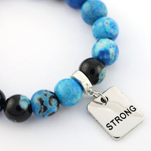 Bracelet with blue and black beads and a 'STRONG' tag on a white background