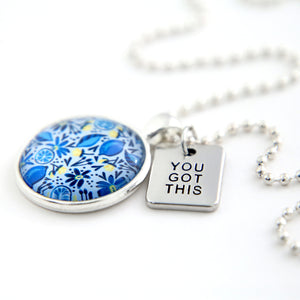 Necklace with blue floral pendant and 'YOU GOT THIS' tag on a white background
