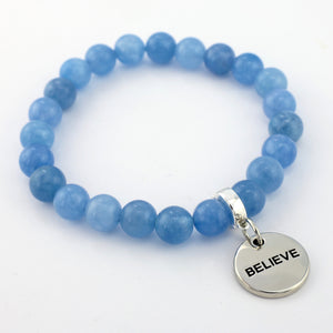 Blue beaded bracelet with a silver 'BELIEVE' charm on a white background