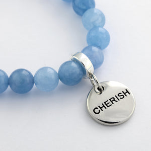 Blue beaded bracelet with a silver charm displaying the word 'CHERISH' on a light background