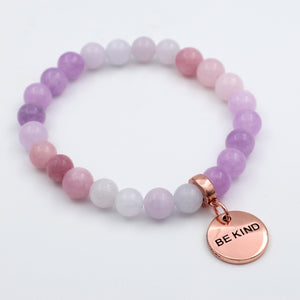 Multicolored beaded bracelet with a 'BE KIND' charm on a white background