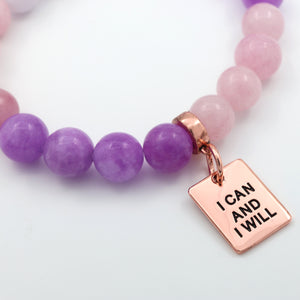 Beaded bracelet with purple and pink beads and a rose gold charm with 'I Can and I Will' text on a white background.