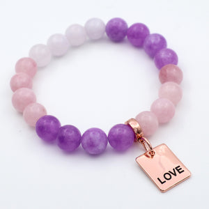 Bracelet with purple and pink beads and a 'LOVE' tag on a white background