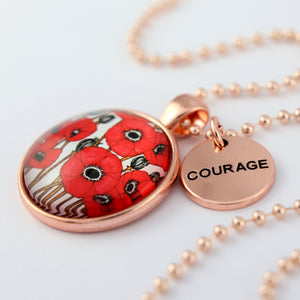 Necklace with red poppy design pendant and 'COURAGE' tag on a white background