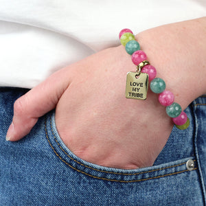 Bracelet with 'Love My Tribe' charm on a wrist, worn with jeans.