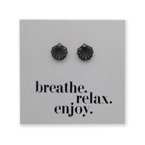 Black shell-shaped earrings on a gray card with 'breathe. relax. enjoy.' text