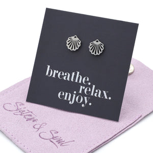 Silver shell earrings on a black card with 'breathe. relax. enjoy.' text, on a purple cloth background.