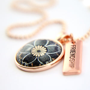 Necklace with floral pendant and 'Friendship' tag on a white background