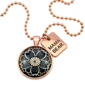 Necklace with 'Mama Bear' tag and black floral pendant on a white background