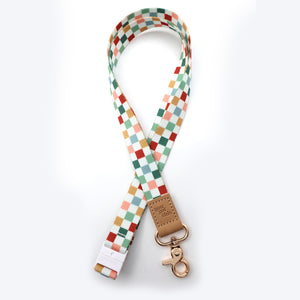 Colorful checkered strap with a brown leather tag and gold clasp on a white background