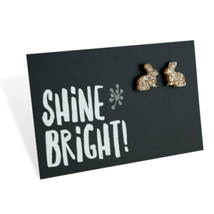 A pair of champagne gold acrylic bunny stud earrings displayed on a black card with the text 'SHINE BRIGHT!' and a star symbol.