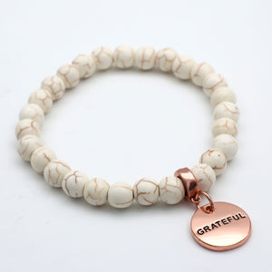 Beaded bracelet with a 'GRATEFUL' charm on a white background