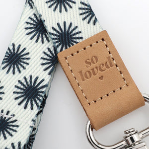 Leather tag with 'so loved' text on a star patterned strap with a keychain.