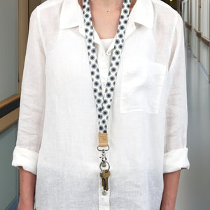 Person wearing a white shirt with a patterned lanyard around their neck.