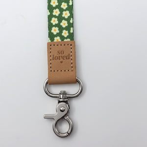 Lanyard with floral pattern and 'so loved' tag on a light gray background