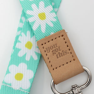 Floral patterned strap with 'you got this' leather tag on a light gray background