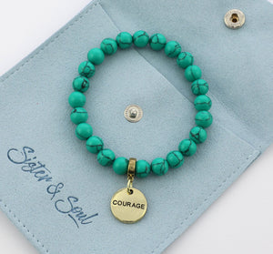 Turquoise beaded bracelet with 'COURAGE' charm on a blue card with 'Sister & Soul' branding.