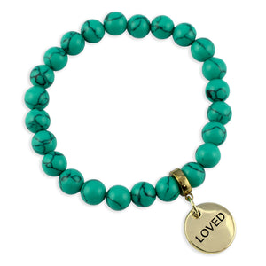 Turquoise beaded bracelet with a gold 'LOVED' charm on a white background