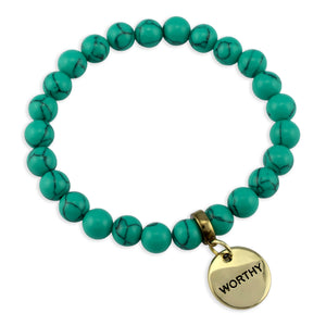 Turquoise beaded bracelet with a gold 'WORTHY' charm on a white background