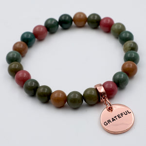 Multicolored beaded bracelet with a 'GRATEFUL' charm on a white background