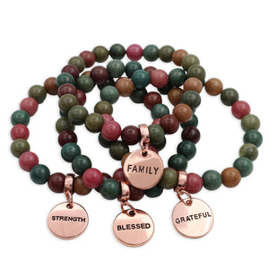 Set of beaded bracelets with rose gold charms on a white background