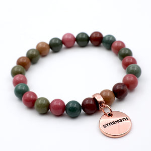 Multicolored beaded bracelet with a 'STRENGTH' charm on a white background