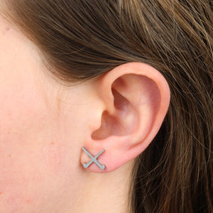 Close-up of an ear wearing a small silver hockey earring design.