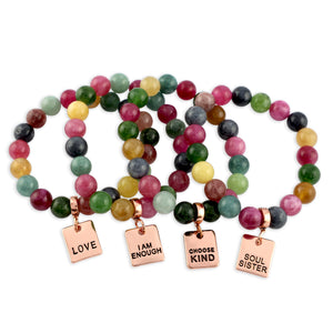 Set of colorful beaded bracelets with inspirational charms on a white background
