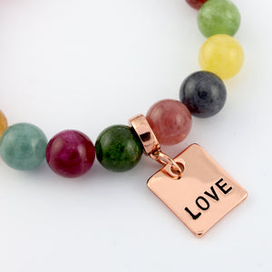 Colorful beaded bracelet with a rose gold 'LOVE' charm on a white background